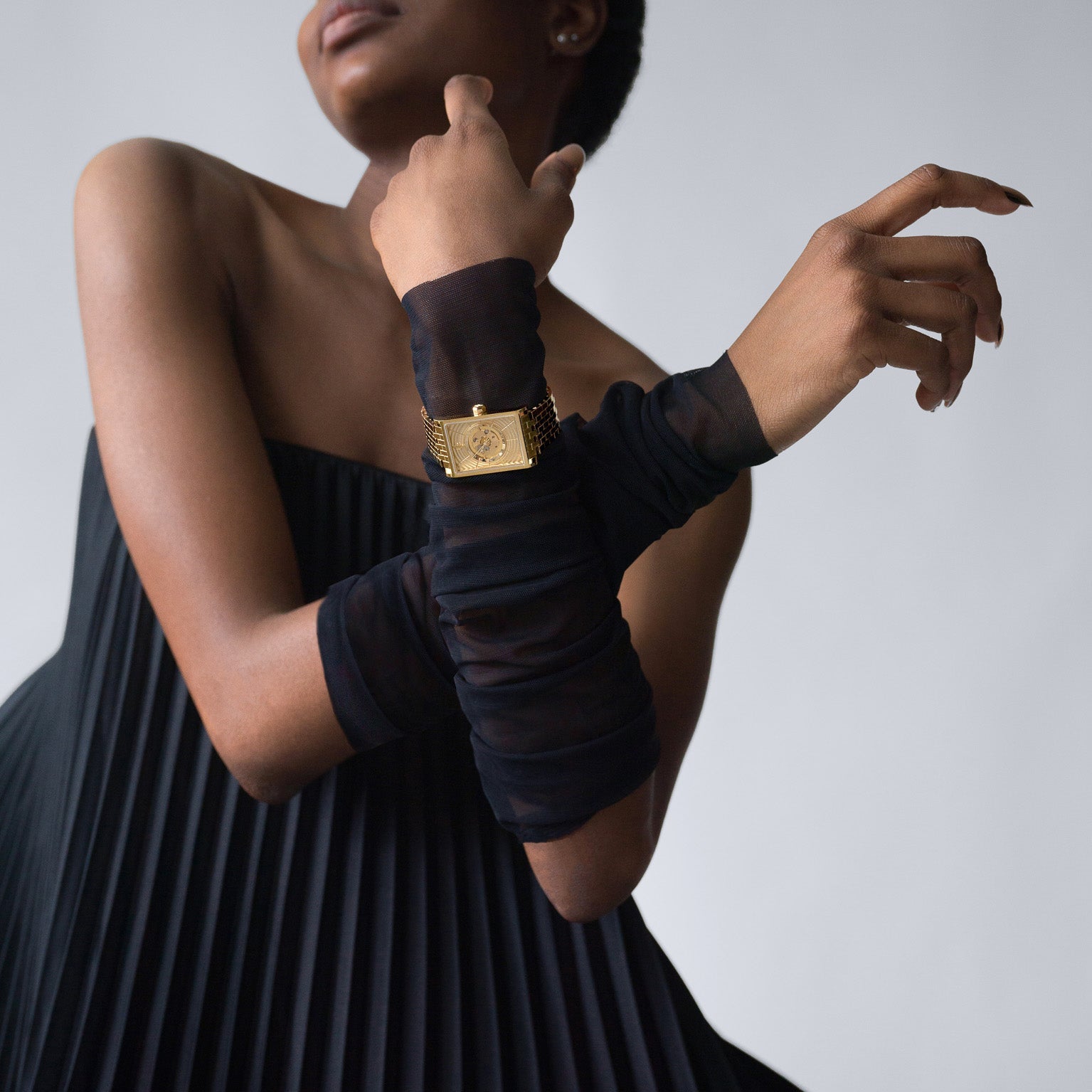 Close-up of a woman wearing a gold Vieren wristwatch paired with sheer black gloves and a pleated strapless dress, photographed by Toronto-based fashion and product photographer Nicholas Hyatt. The image emphasizes luxury styling and contemporary elegance.